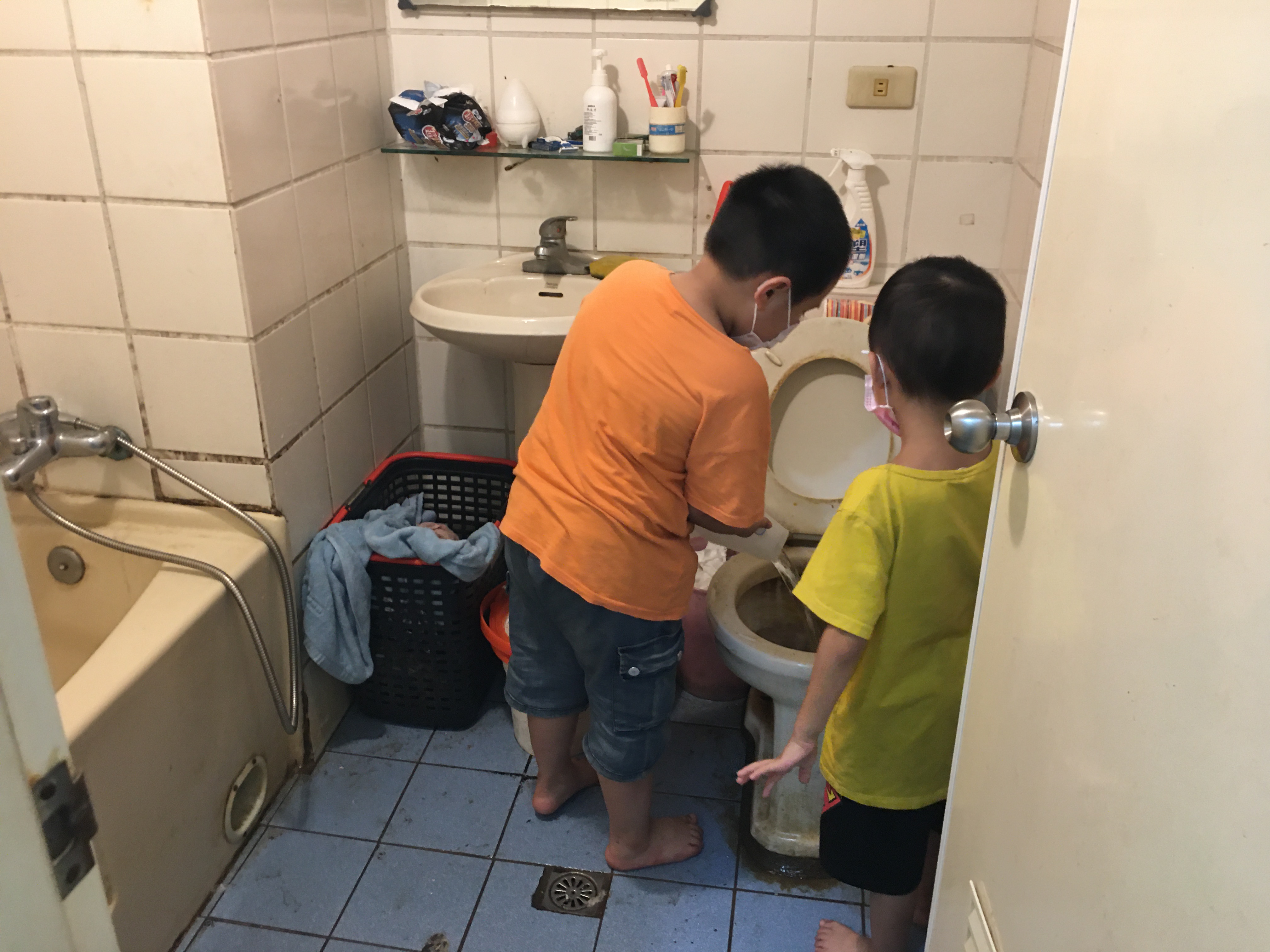 讀小二的長子小杰（左）幫忙臥床養傷的父親清洗尿桶，右為6歲次子。向高彬攝