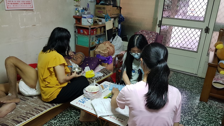 阿珍（左前）照料罹肝硬化的先生阿宗（左後）吃飯，讀高三的次女（右前）、讀高二的參女在一旁將爸藥丸置入藥盒，方便媽媽幫爸餵藥。韓旭爾攝