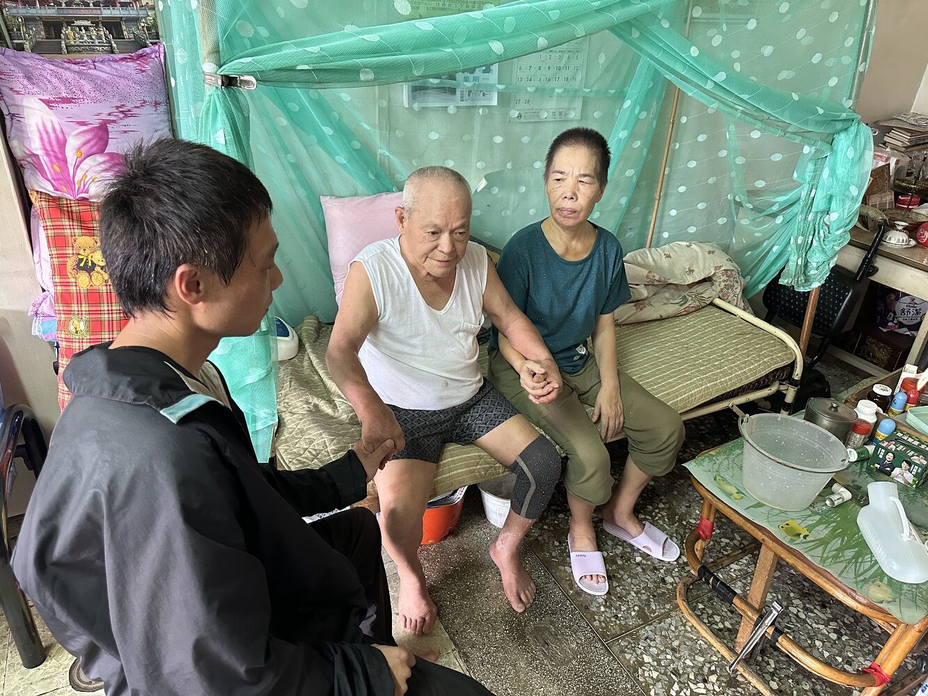 阿軒(左)的爸爸阿安伯(中)頸椎受損，媽媽阿錦嬤也中風，阿軒1人難看顧，暫時由外勞協助照顧爸爸。江品璁攝