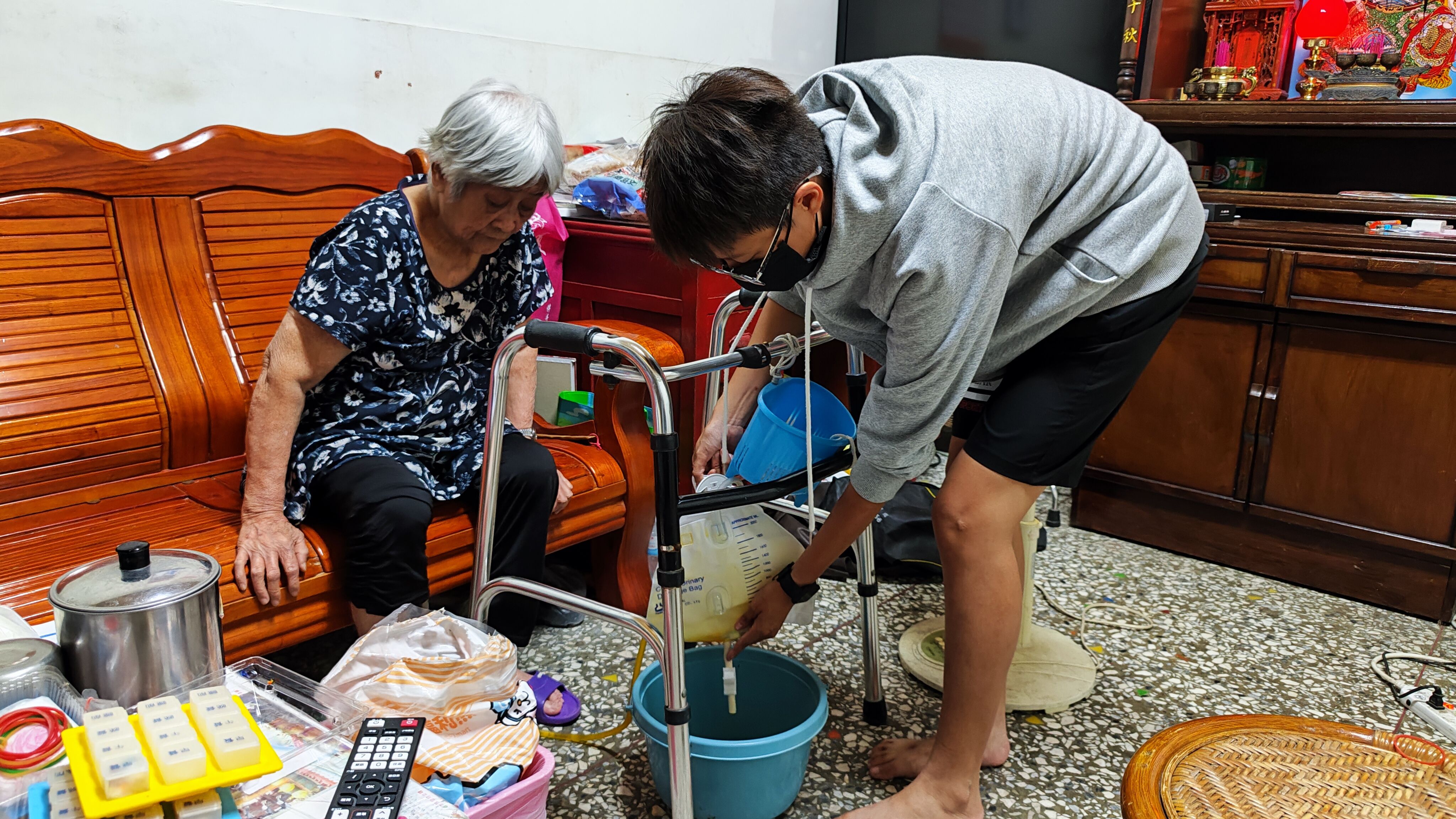 小岑也協助照料罹患失智症、行動不便的阿嬤，她正幫忙倒尿袋。韓旭爾攝