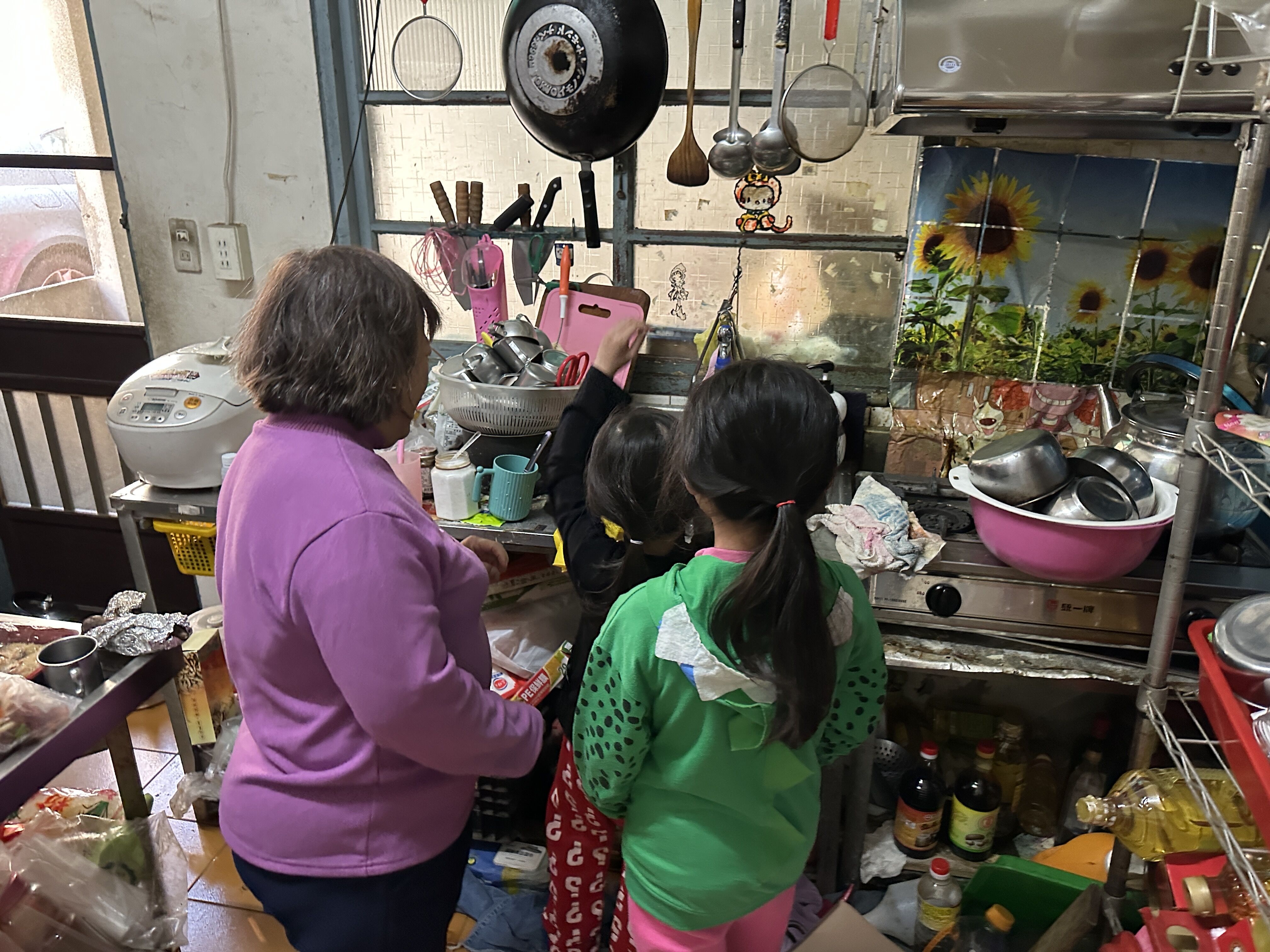 阿月姨的女兒自喪夫後，就孩子帶回娘家同住，外孫女小玉(右)與小惠(中)也會幫忙洗碗做家事。江品璁攝