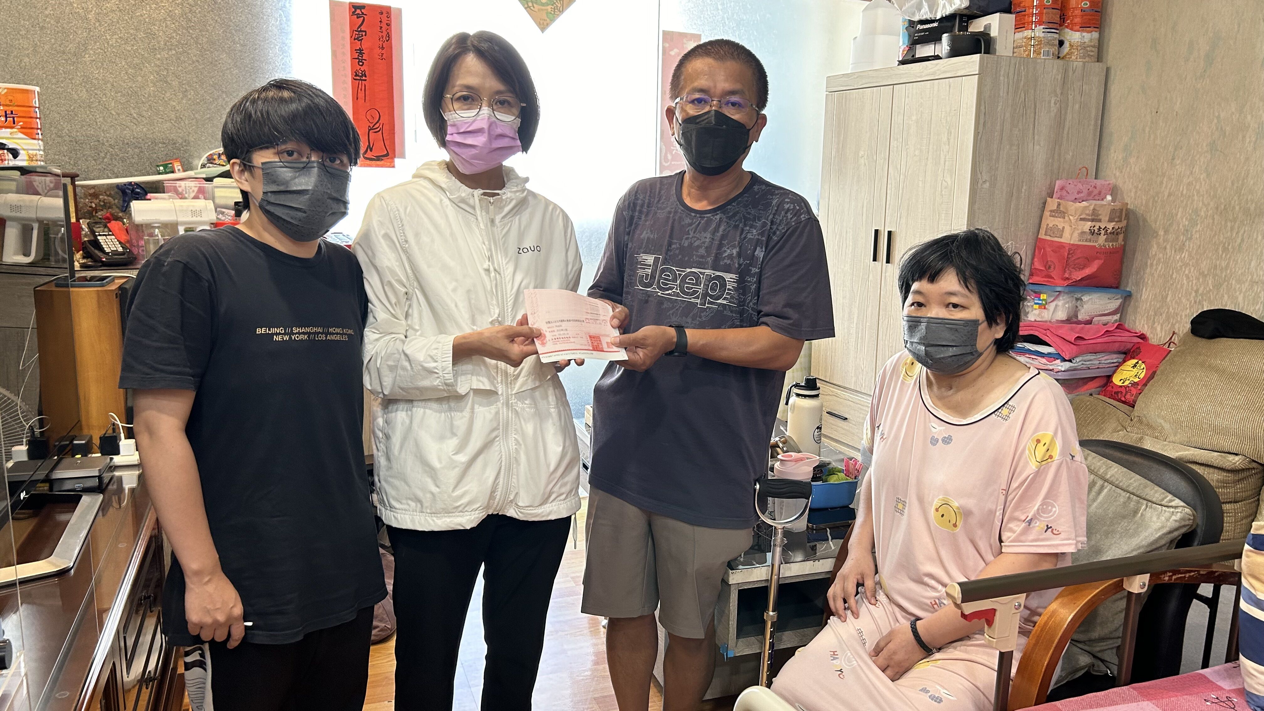 54歲阿洲叔（右二）與腦傷半癱太太阿華嬸（右一）、患思覺失調症次女阿徽（左一）經里長張育綺見證，收下讀者善款。仲芝蓉攝